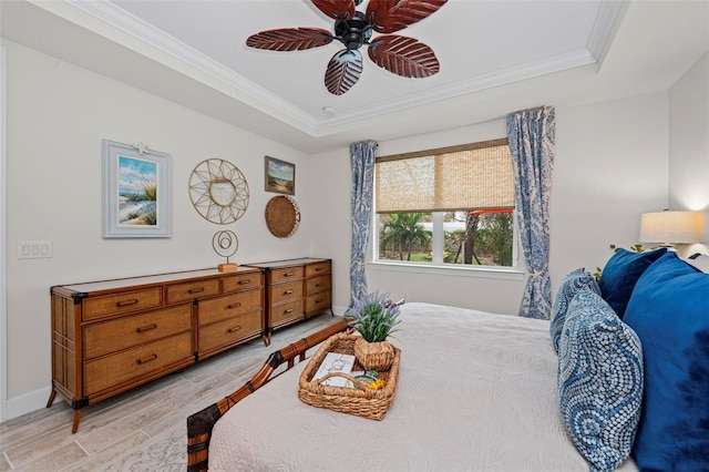 bedroom featuring crown molding, a tray ceiling, light wood-type flooring, and ceiling fan