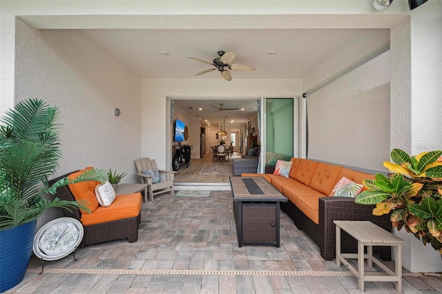 view of patio featuring ceiling fan and an outdoor living space with a fire pit