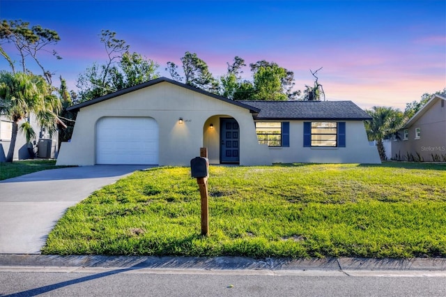 single story home featuring a garage and a yard