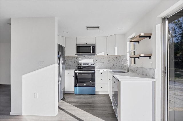 kitchen with hardwood / wood-style floors, backsplash, sink, white cabinetry, and stainless steel appliances