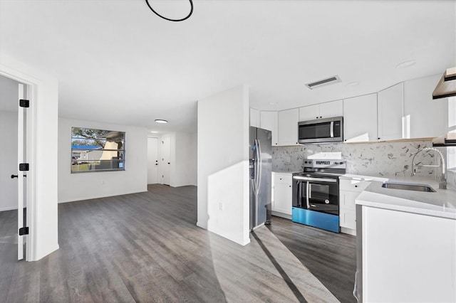 kitchen with appliances with stainless steel finishes, dark hardwood / wood-style flooring, white cabinetry, and sink