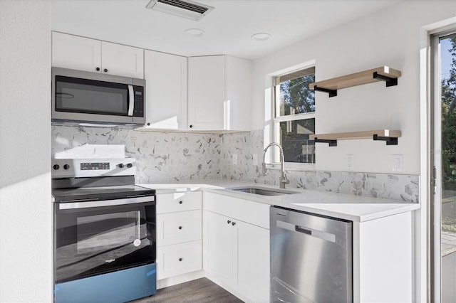 kitchen with dark hardwood / wood-style flooring, tasteful backsplash, stainless steel appliances, sink, and white cabinetry