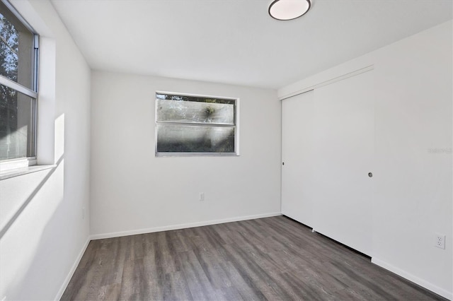 empty room with dark hardwood / wood-style flooring and a wealth of natural light