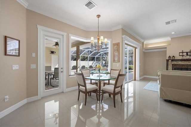 tiled dining space featuring ornamental molding, a wealth of natural light, and ceiling fan with notable chandelier