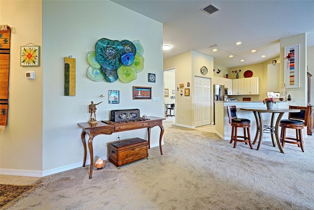 kitchen featuring a kitchen breakfast bar, stainless steel refrigerator with ice dispenser, and light carpet