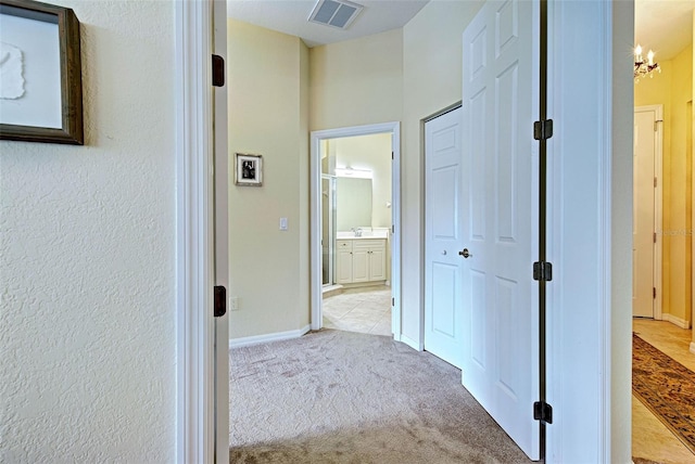 corridor featuring a chandelier and light colored carpet