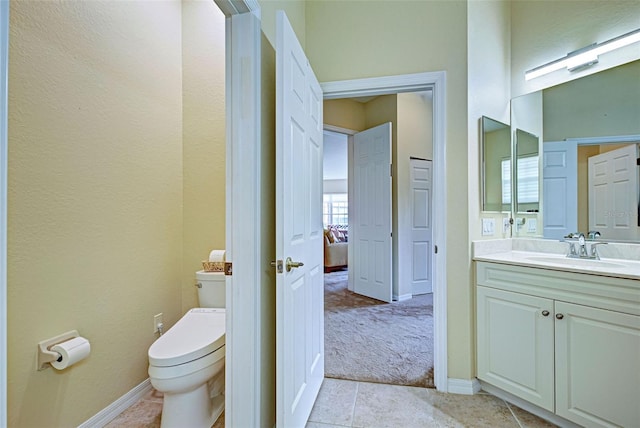 bathroom with toilet, vanity, and tile patterned flooring