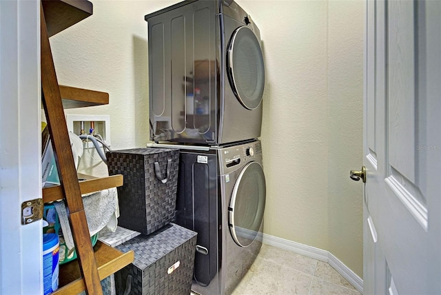 laundry room featuring stacked washer / dryer and light tile patterned floors