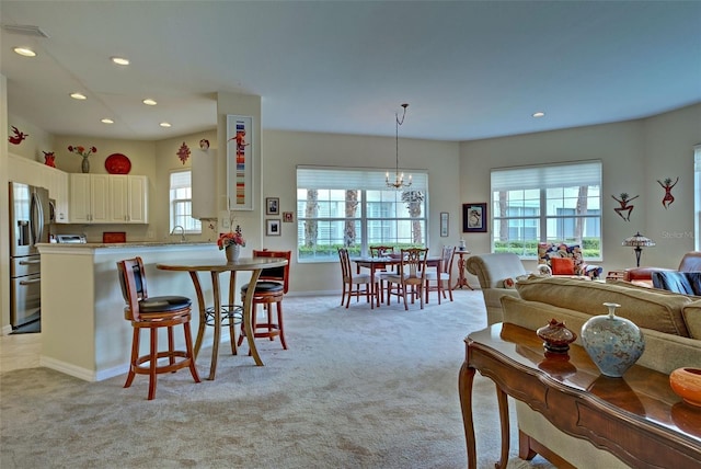 kitchen with light carpet, stainless steel fridge, a kitchen breakfast bar, a notable chandelier, and decorative light fixtures