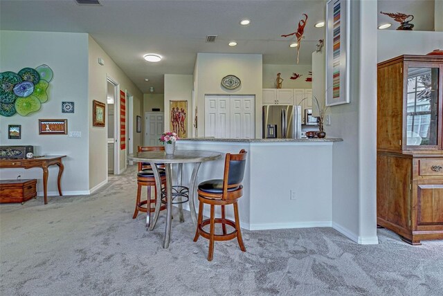 1704 Triano Cir Unit 1704, Venice, FL 34292 - kitchen featuring appliances with stainless steel finishes, light carpet, white cabinets, baseboards, and a breakfast bar area