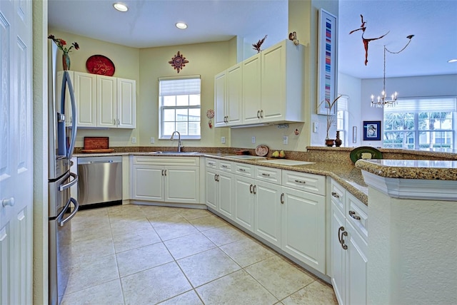 kitchen with dishwasher, sink, a notable chandelier, pendant lighting, and white cabinets