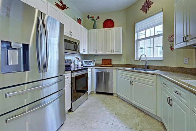 kitchen with light tile patterned floors, appliances with stainless steel finishes, sink, and white cabinets