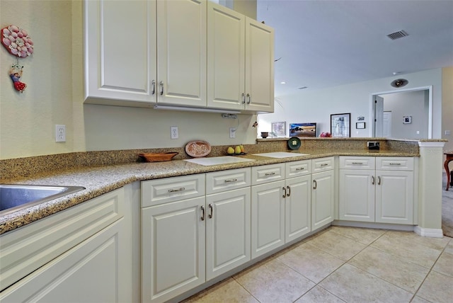 kitchen featuring white cabinetry, kitchen peninsula, and light tile patterned flooring