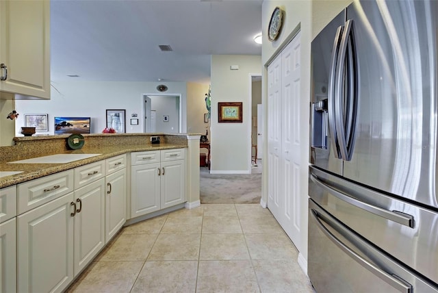 kitchen featuring white cabinets, light stone counters, light carpet, and stainless steel refrigerator with ice dispenser