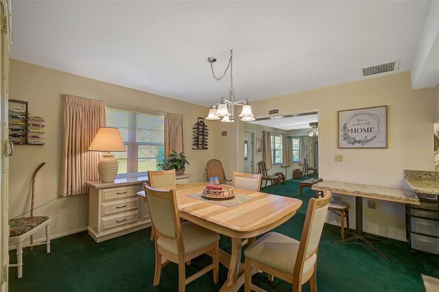 1402 Grand Blvd Unit 240, Sarasota, FL 34232 - dining area with dark colored carpet, a ceiling fan, and a chandelier