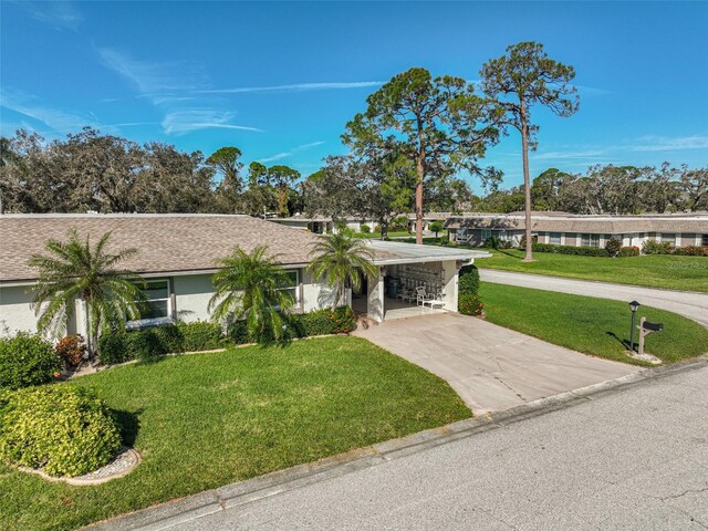 1402 Grand Blvd Unit 240, Sarasota, FL 34232 - view of front of house with driveway, a front yard, a carport, stucco siding, and roof with shingles