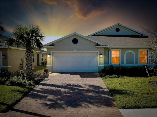 single story home featuring a garage and a lawn