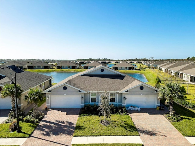 ranch-style house featuring a front yard, a garage, and a water view