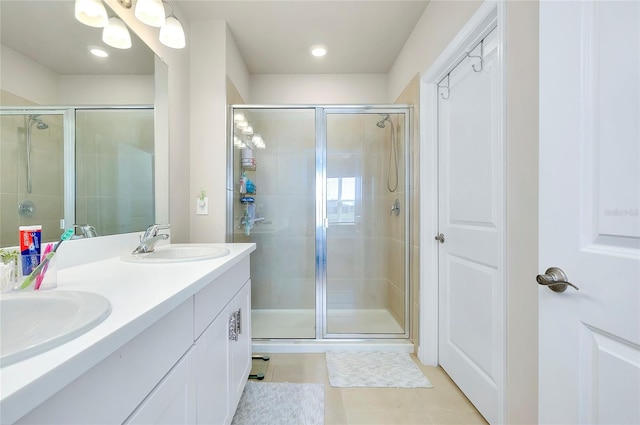 bathroom with a shower with door, vanity, and tile patterned flooring