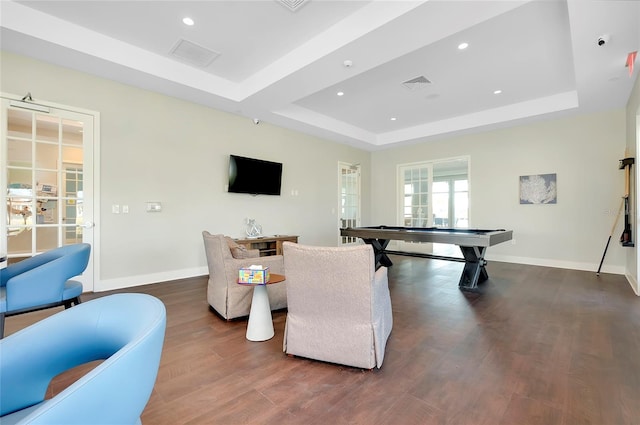 rec room with dark hardwood / wood-style floors and a raised ceiling