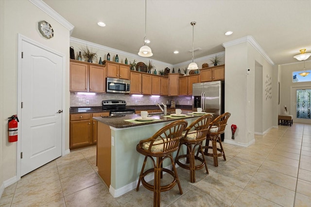 kitchen featuring appliances with stainless steel finishes, ornamental molding, an island with sink, and decorative backsplash