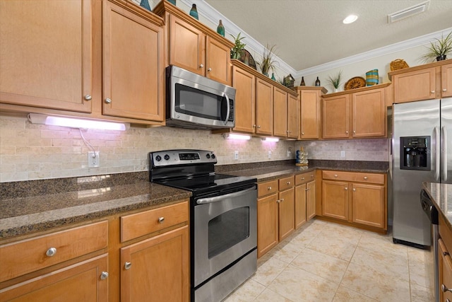 kitchen with decorative backsplash, light tile patterned floors, ornamental molding, dark stone countertops, and stainless steel appliances