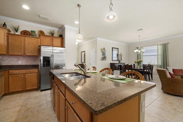 kitchen featuring appliances with stainless steel finishes, sink, decorative light fixtures, crown molding, and a kitchen island with sink