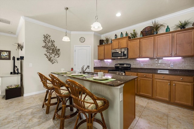 kitchen featuring sink, appliances with stainless steel finishes, ornamental molding, and an island with sink