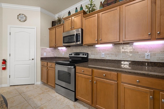 kitchen with decorative backsplash, light tile patterned floors, dark stone counters, crown molding, and stainless steel appliances