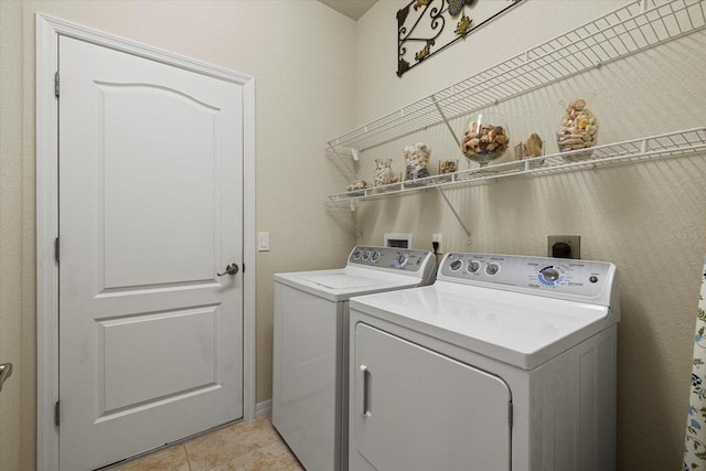 clothes washing area with washer and clothes dryer and light tile patterned floors