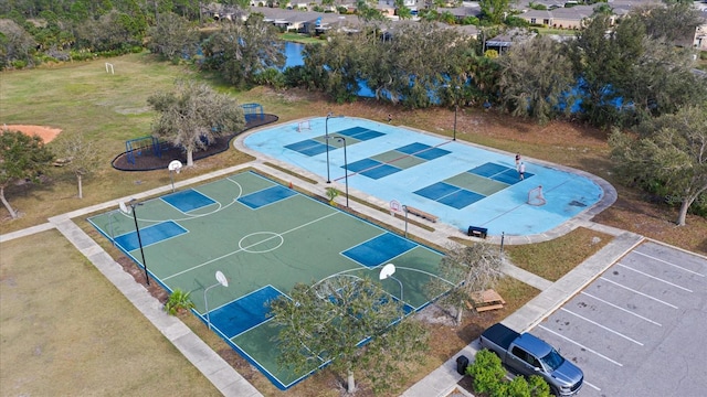 view of sport court with a water view and a lawn