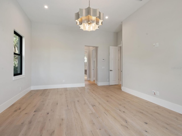 unfurnished room featuring light hardwood / wood-style flooring and an inviting chandelier