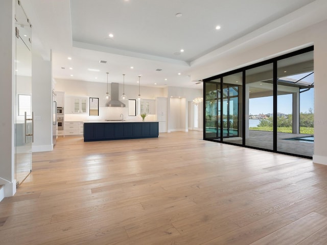 unfurnished living room with sink, a notable chandelier, and light wood-type flooring