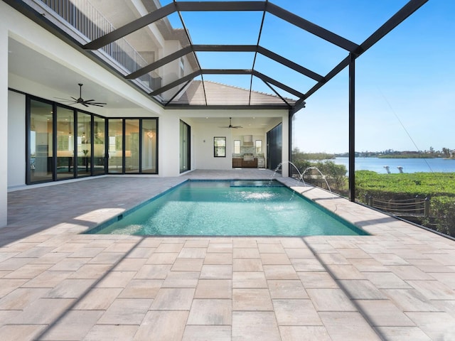 view of swimming pool with glass enclosure, a water view, pool water feature, ceiling fan, and a patio area