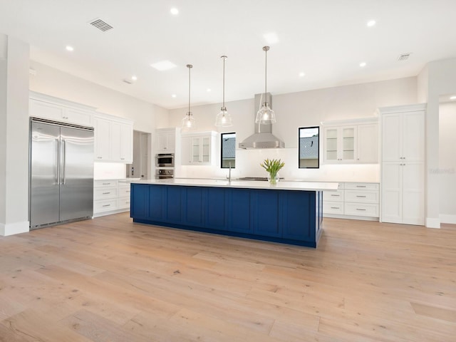 kitchen featuring white cabinetry, wall chimney range hood, and stainless steel appliances