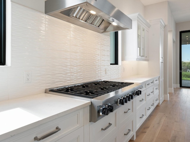 kitchen featuring white cabinetry, backsplash, light hardwood / wood-style floors, extractor fan, and stainless steel gas stovetop