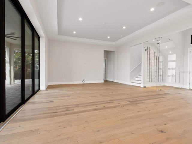 unfurnished room with light wood-type flooring and a tray ceiling