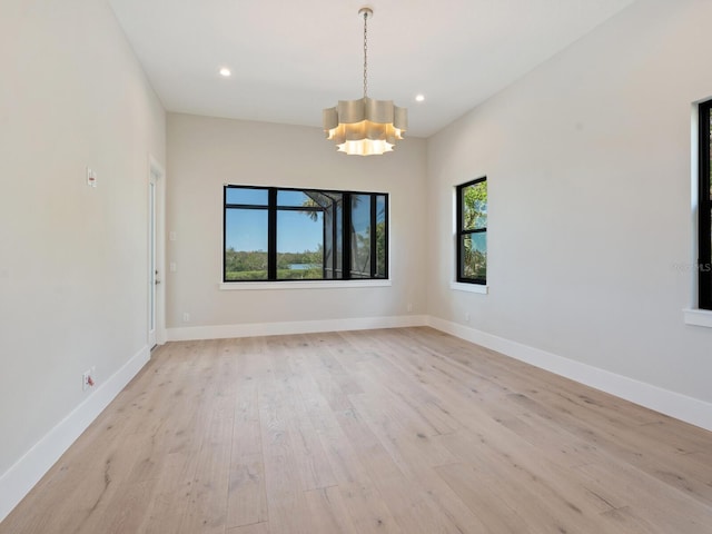 unfurnished room with a notable chandelier and light hardwood / wood-style flooring