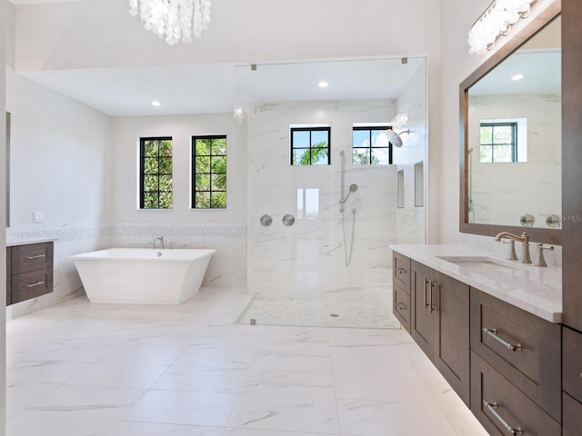 bathroom with a notable chandelier, vanity, separate shower and tub, and tile walls