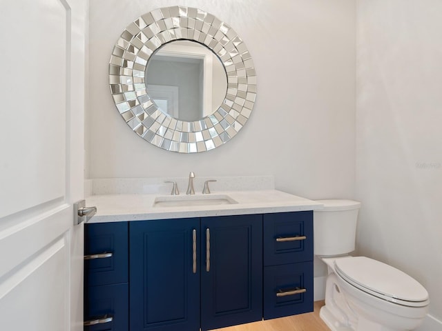 bathroom with hardwood / wood-style floors, vanity, and toilet