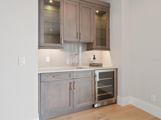 bar featuring sink, wine cooler, and light hardwood / wood-style flooring