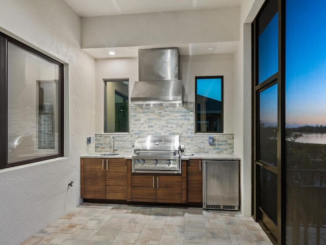 kitchen featuring backsplash, fridge, wall chimney exhaust hood, and sink