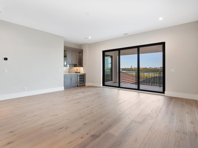 unfurnished living room with beverage cooler and light hardwood / wood-style flooring