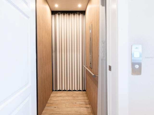 hallway featuring light wood-type flooring and elevator