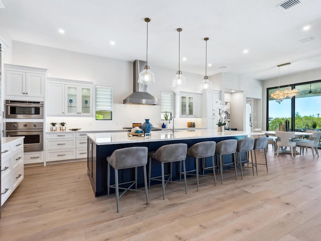 1109 Bayshore Rd, Nokomis, FL 34275 - kitchen with wall chimney range hood, decorative backsplash, light countertops, a large island with sink, and white cabinets