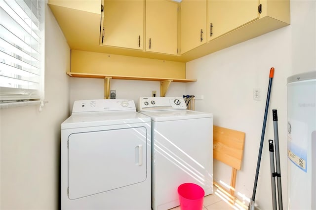 washroom featuring water heater, cabinets, and washing machine and clothes dryer