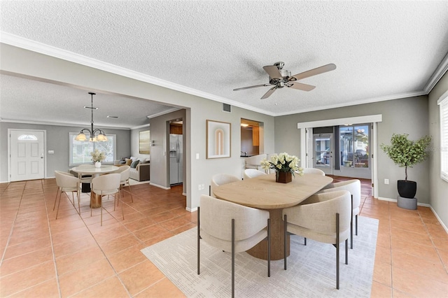 dining room with light tile patterned flooring, a textured ceiling, ornamental molding, and ceiling fan with notable chandelier