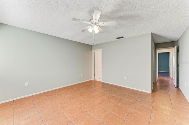 tiled spare room with a textured ceiling and ceiling fan