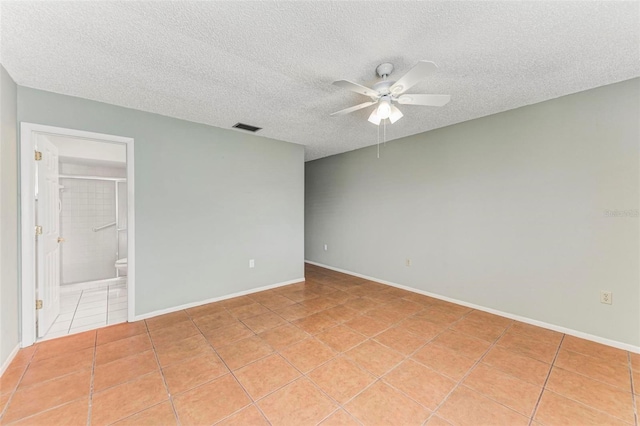 empty room featuring a textured ceiling, light tile patterned flooring, and ceiling fan