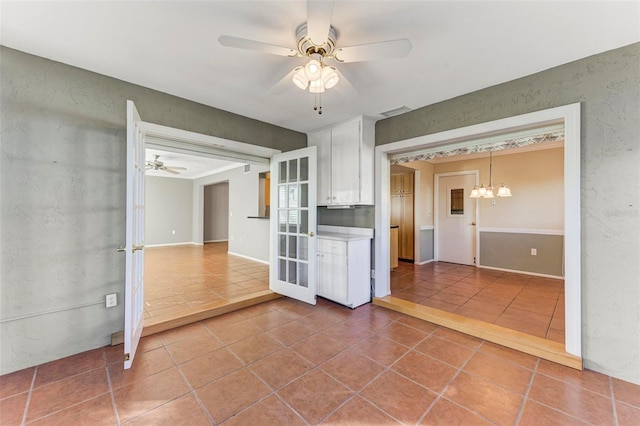 interior space with tile patterned floors and ceiling fan with notable chandelier